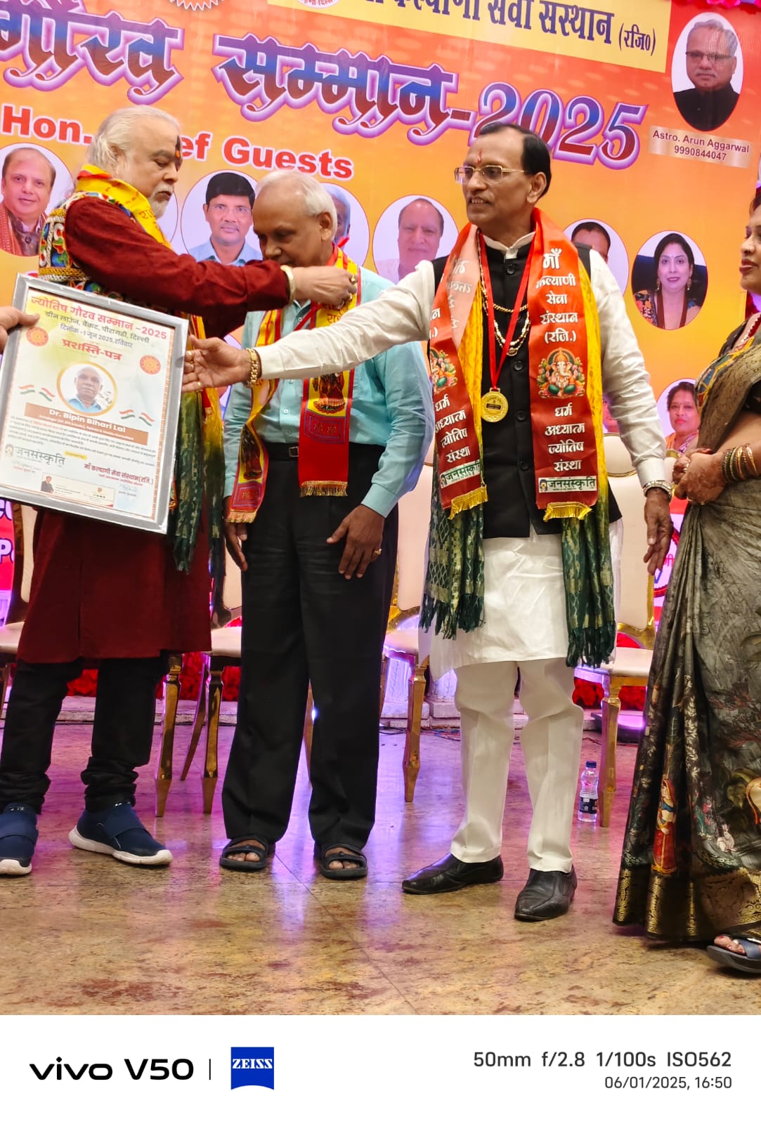 Dr. Bipin Bihari Lal being felicitated on stage at a recognition ceremony, wearing a medal and shawl.