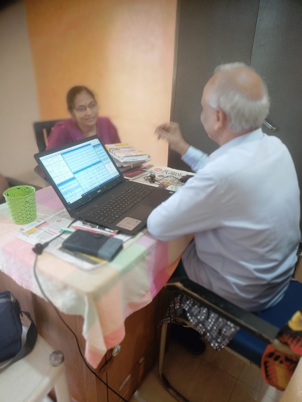 Dr. Bipin Bihari Lal in consultation with a client at his desk, with a chart displayed on his laptop.